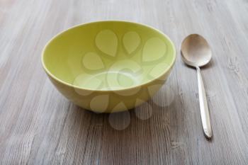 one green bowl and spoon on gray brown table