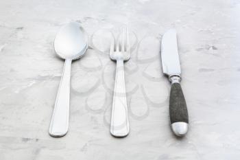 food concept - flatware set from table knife, fork, soup spoon on concrete surface