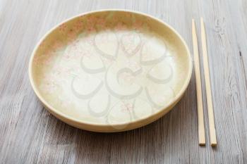 one yellow green plate and chopsticks on gray brown table