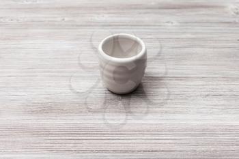 food concept - white ceramic cup for sake (ochoko, choko) on gray brown wooden table