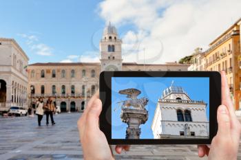 travel concept - tourist photographs winged lion on piazza dei Signori in Padua city on tablet in Italy