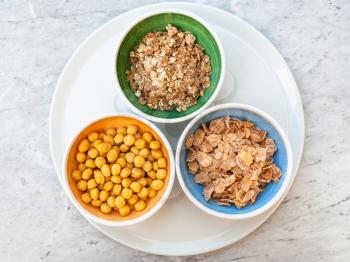 top view of three kind of cold breakfast cereals in bowls on white plate