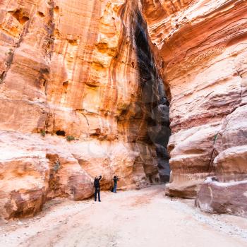 PETRA, JORDAN - FEBRUARY 21, 2012: tourists on way in Al Siq gorge to ancient Petra town in winter. Rock-cut town Petra was established about 312 BC as the capital city of the Arab Nabataean