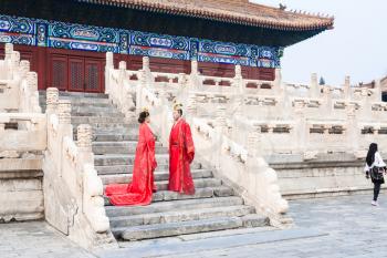 BEIJING, CHINA - MARCH 19, 2017: couple in red dresses on steps of Hall for Worship of Ancestors in Imperial Ancestral Temple (Taimiao) in Beijing Imperial city in spring.