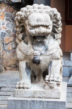 LUOYANG, CHINA - MARCH 20, 2017: stone lion statue near temple of Chinese Buddhist monument Longmen Grottoes in spring. The complex was inscribed upon the UNESCO World Heritage List in 2000