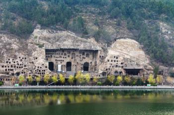LUOYANG, CHINA - MARCH 20, 2017: View of Caves on West Hill of Chinese Buddhist monument Longmen Grottoes (Longmen Caves, Dragon's Gate) from the east bank of the Yi River in spring season