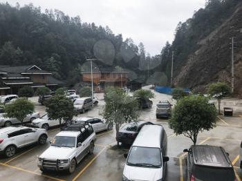DAZHAI, CHINA - MARCH 23, 2017: cars on parking lot near gate of Dazhai Longsheng village in spring. This is central village in famous scenic area of Longji Rice Terraces in China