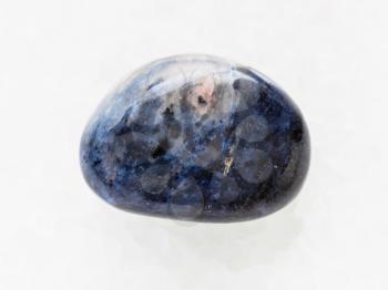 macro shooting of natural mineral rock specimen - polished dumortierite gem stone on white marble background
