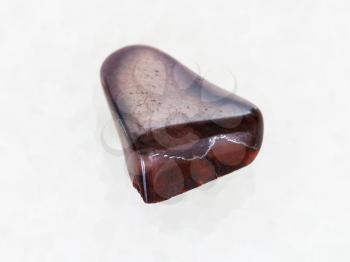 macro shooting of natural mineral rock specimen - polished jaspilite jasper gemstone on white marble background