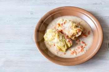 russian cuisine - top view of stewed cabbage rolls on ceramic plate on gray wooden table with copyspace