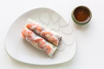 top view of served Nem cuon (fresh Vietnamese nem roll with shrimps, mango and ginger) on white plate on white board