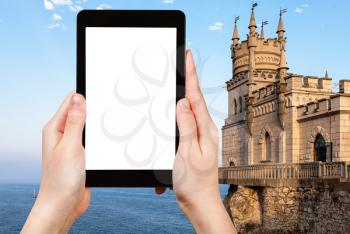travel concept - tourist photographs Swallow Nest Castle over Black Sea in Gaspra District on Crimean Southern Coast in september evening on tablet with cut out screen for advertising logo