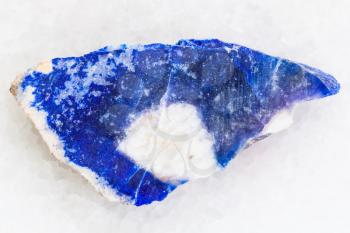 macro shooting of natural mineral rock specimen - raw lazurite (lapis lazuli) stone on white marble background