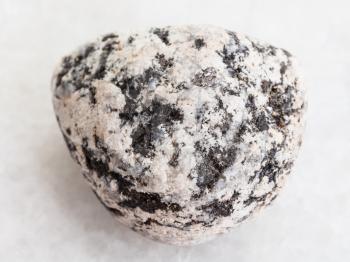 macro shooting of natural mineral rock specimen - pebble of Diorite stone on white marble background