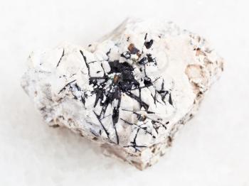macro shooting of natural mineral rock specimen - Ilmenite black crystals on raw stone on white marble background from Khibiny Mountains, Kola Peninsula in Russia