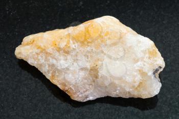 macro shooting of natural mineral rock specimen - raw yellow Calcite stone on dark granite background
