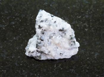 macro shooting of natural mineral rock specimen - rough Diorite stone on dark granite background