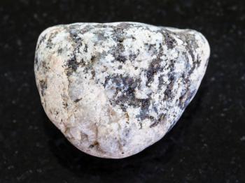 macro shooting of natural mineral rock specimen - piece of Diorite stone on dark granite background