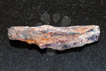 macro shooting of natural mineral rock specimen - raw Schist stone with Kyanite crystal on dark granite background