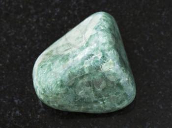 macro shooting of natural mineral rock specimen - polished green Jadeite gemstone on dark granite background