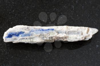macro shooting of natural mineral rock specimen - raw blue kyanite stone on dark granite background from Brazil