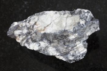 macro shooting of natural mineral rock specimen - native Bismuthinite in raw quartz stone on dark granite background from Malkhanskoye mine (Malkhan) from Transbaikal region of Russia