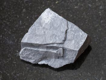 macro shooting of natural mineral rock specimen - rough argillite stone on dark granite background