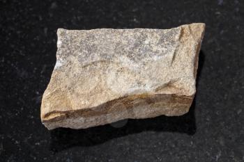 macro shooting of natural mineral rock specimen - rough polymictic sandstone stone on dark granite background