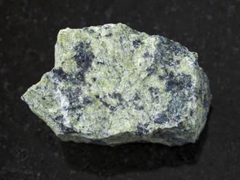 macro shooting of natural mineral rock specimen - rough serpentinite stone on dark granite background