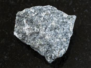 macro shooting of natural mineral rock specimen - rough Diorite stone on dark granite background