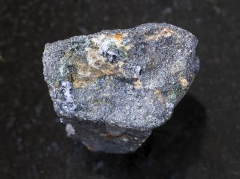 macro shooting of natural mineral rock specimen - rough Molybdenite stone on dark granite background from Kabardino-Balkaria, North Caucasus, Russia