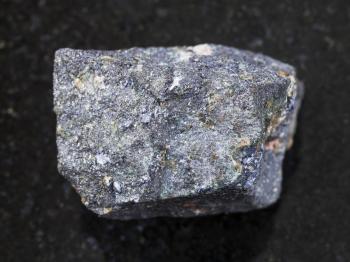 macro shooting of natural mineral rock specimen - raw Molybdenite stone on dark granite background from Kabardino-Balkaria, North Caucasus, Russia