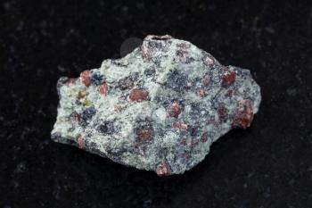 macro shooting of natural mineral rock specimen - raw eclogite stone on dark granite background from Salma region, Kola peninsula, Russia