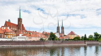 travel to Poland - view of Collegiate Church of the Holy Cross and St Bartholomew and towers of Cathedral of St John the Baptist in Ostrow Tumski district in Wroclaw city from Oder River