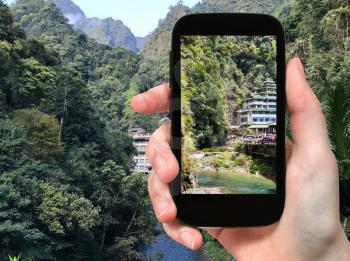 travel concept - tourist photographs mountain brook in Longsheng Hot Springs National Forest Park in Jiangdi village of Xiangshan District in China in spring season on smartphone