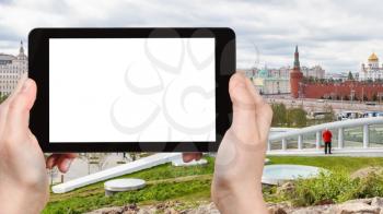 travel concept - tourist photographs Zaryadye urban park and Kremlin Walls on embankment in Moscow city in autumn on tablet with cut out screen for advertising logo