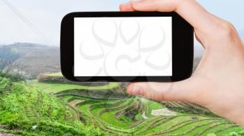 travel concept - tourist photographs Rice Terraces near Tiantouzhai village in Dazhai Longsheng (Dragon's Backbone, Longji) county in spring on smartphone with cut out screen for advertising logo