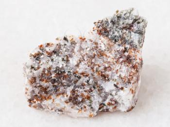 macro shooting of natural mineral rock specimen - brown chondrodite and green diopside crystals in rough calcite stone on white marble background from Pitkyaranta region of Karelia, Russia
