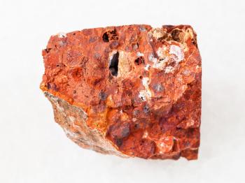 macro shooting of natural mineral rock specimen - rough red bauxite stone on white marble background