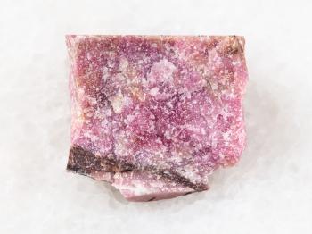 macro shooting of natural mineral rock specimen - raw rhodonite stone on white marble background from Ural Mountains