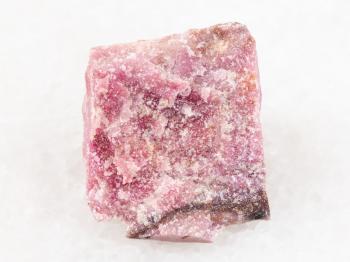 macro shooting of natural mineral rock specimen - rough rhodonite stone on white marble background from Ural Mountains