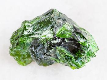 macro shooting of natural mineral rock specimen - raw crystal of Chrome Diopside gemstone on white marble background from Inagli (Inaglinskoe mine) in Yakutia, Siberia, Russia