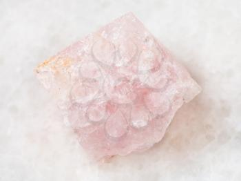 macro shooting of natural mineral rock specimen - rough crystal of morganite (pink beryl) gemstone on white marble background from Mozambique