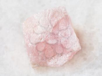 macro shooting of natural mineral rock specimen - raw crystal of morganite (pink beryl) gemstone on white marble background from Mozambique