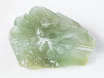 macro shooting of natural mineral - rough Prase (green quartz) stone on white marble from Ural Mountains