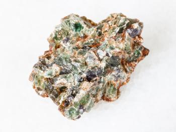 macro shooting of natural mineral - green beryl and emerald crystals in raw rock on white marble from Ural Mountains