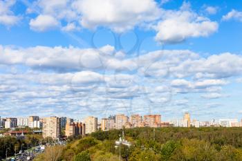 white clouds in blue sky over street and urban park in sunny autumn day