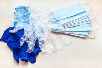 heaps of disposable protective face masks and hand gloves on light brown table