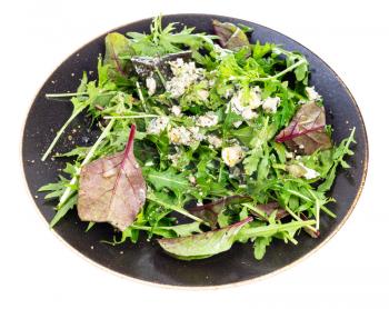 fresh salad from chard and arugula with blue cheese, pepper and olive oil on dark brown plate isolated on white background