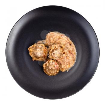 top view of meatballs with rice with creamy tomato sauce on black plate isolated on white background